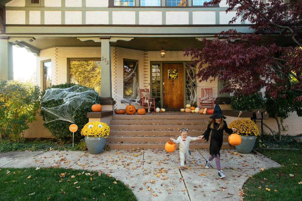 Child dressed as a ghost for Halloween standing next to a Vivint sign.