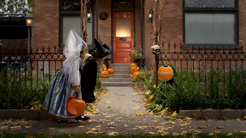 Kids dressed up for Halloween walking to a doorstep to trick-or-treat.