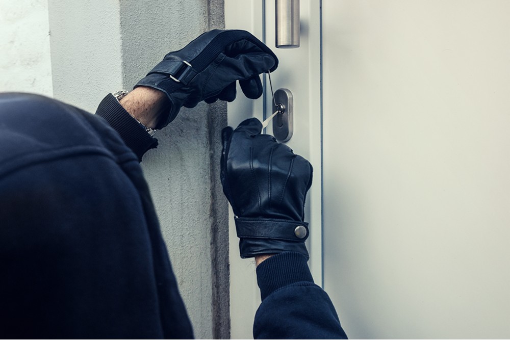 Thief breaking into someone's front door.