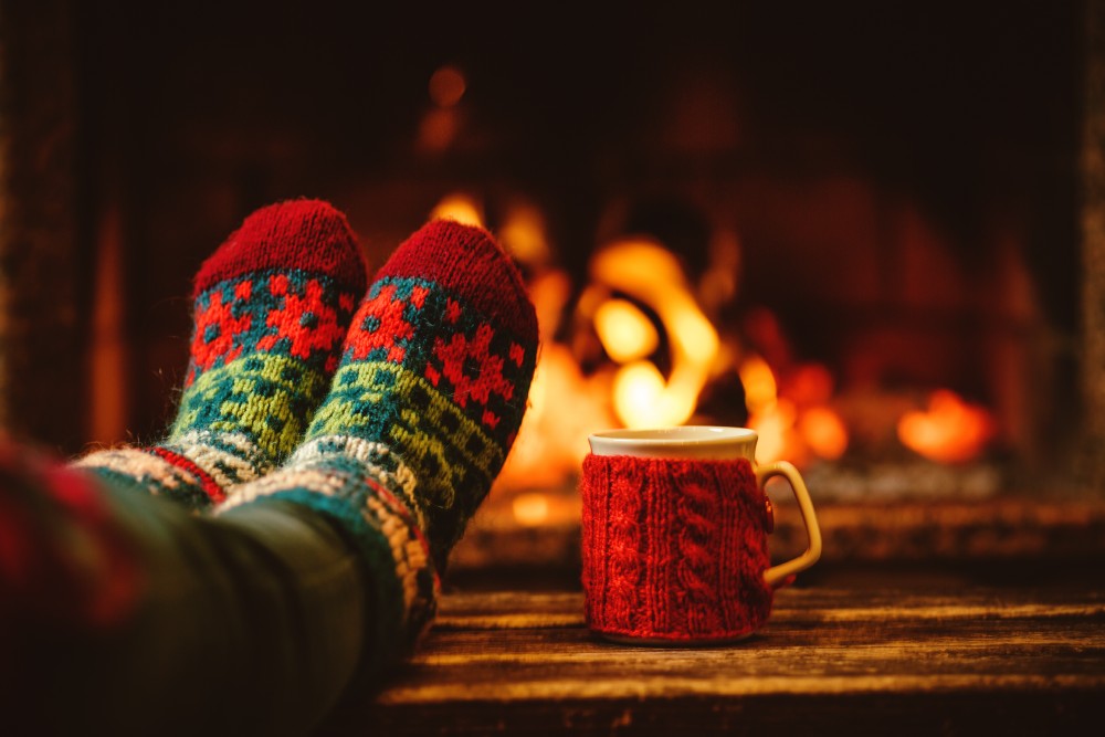 Someone wearing Christmas socks sitting in front of a warm fire.