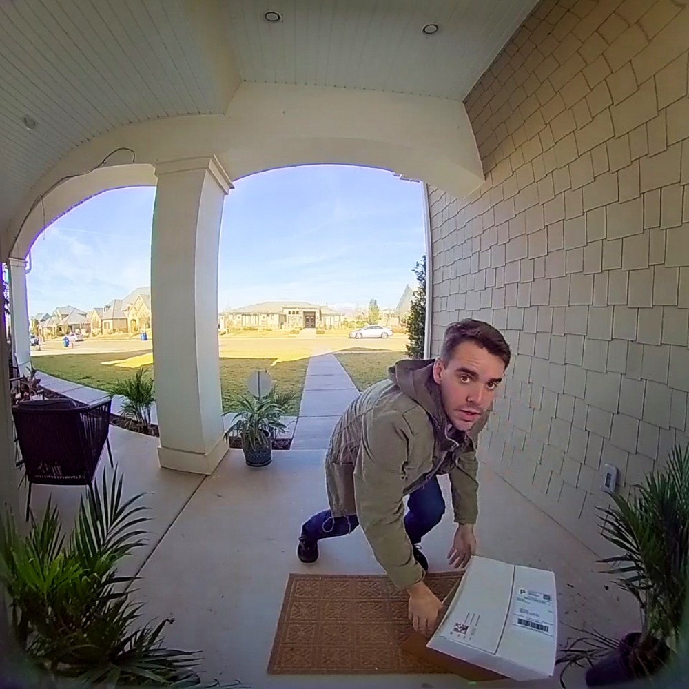 Burglar attempting to steal packages off a front porch.