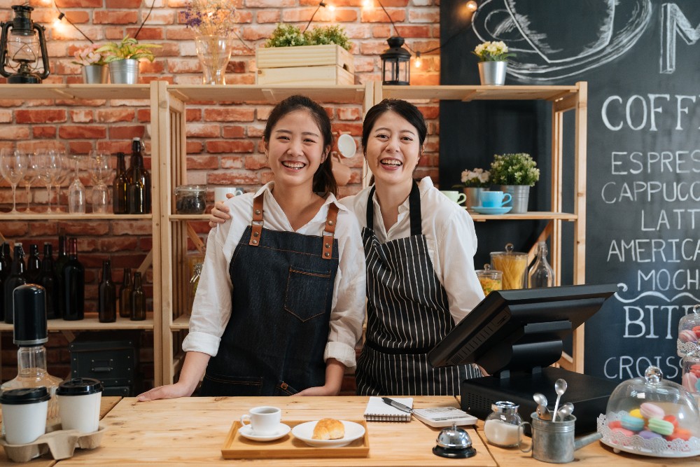 Mother and daughter standing behind at the cash register at their small business.