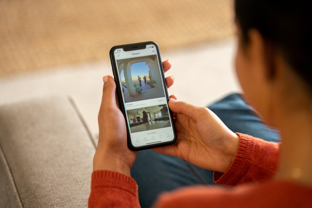 Woman using the Vivint app to see her front porch from the comfort of her couch.