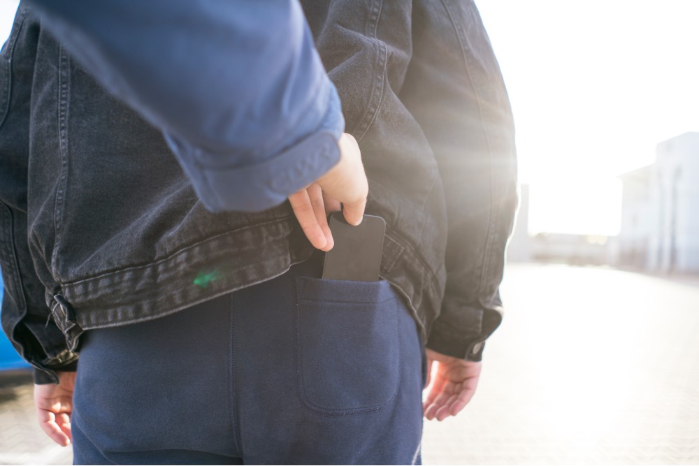 A pickpocketer taking someone's phone out of their back pocket.