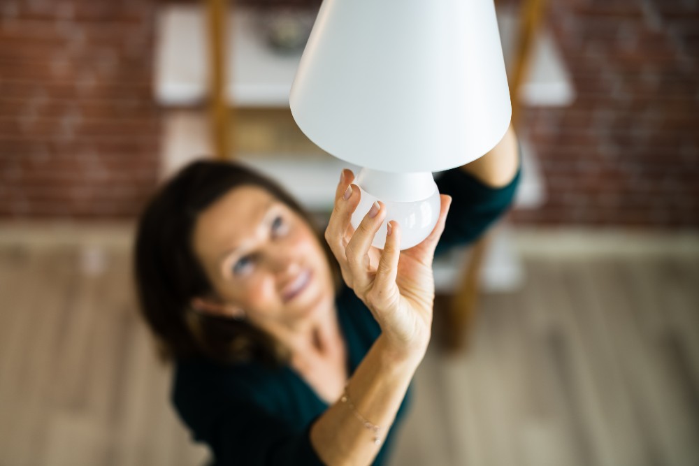 Woman screwing in a smart lightbulb.