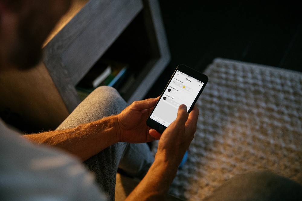 Man changing the brightness on his lightbulbs with the Philips Hue app.