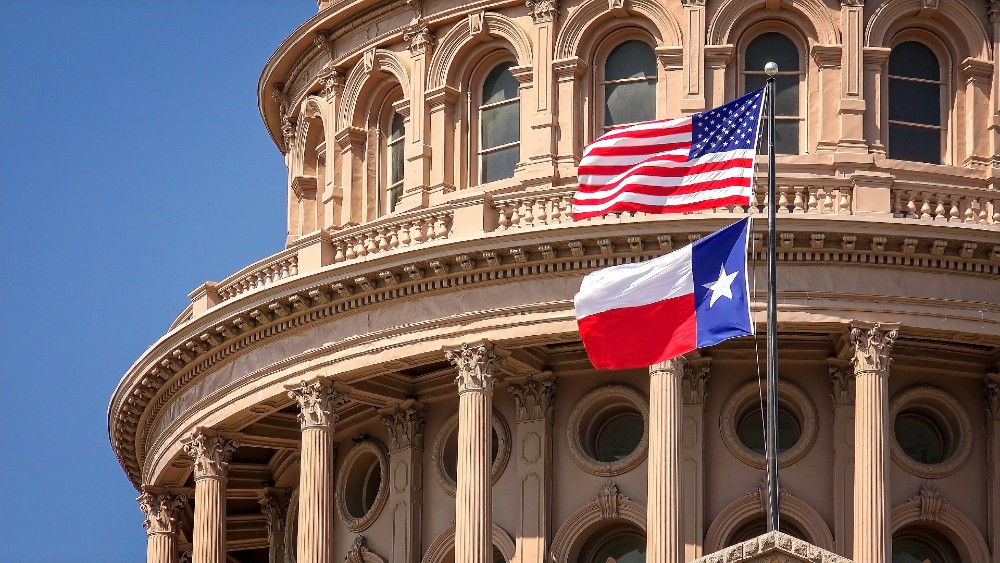 American and Texas flags flying on the dome of the Texas state capitol building in Austin, Texas