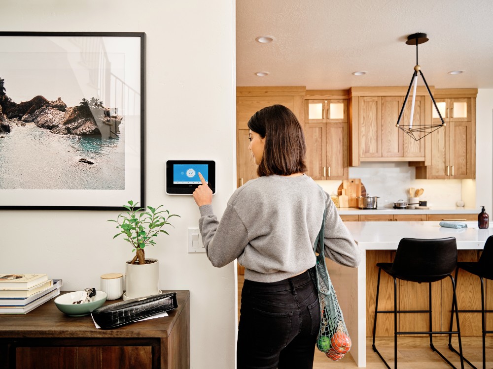 Person touching Vivint Smart Hub holding bag of groceries