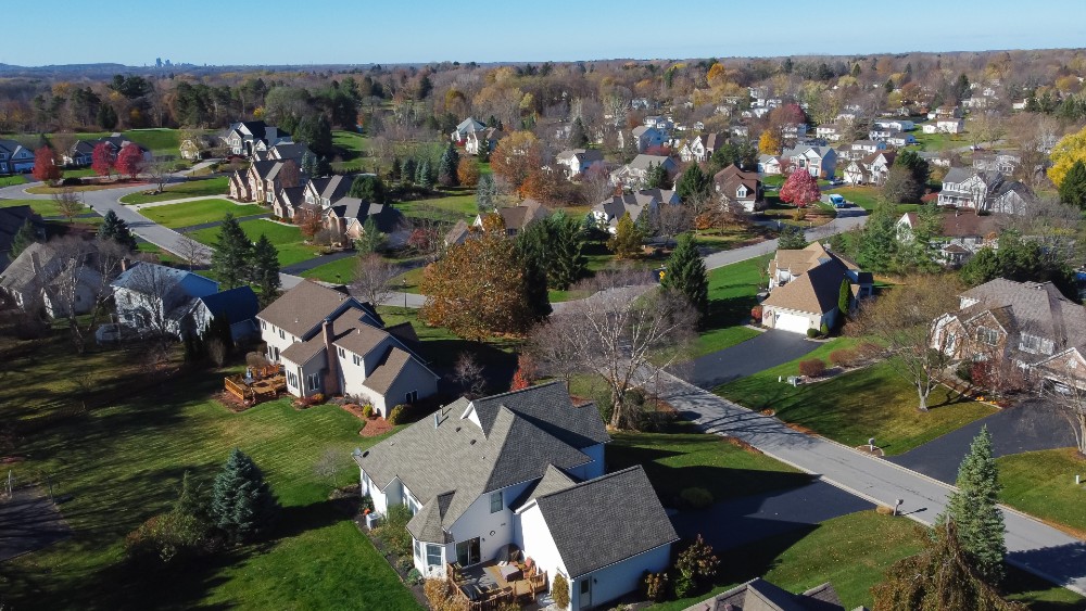 Two-story suburban houses in low density housing neighborhood with downtown Rochester building in background upstate New York