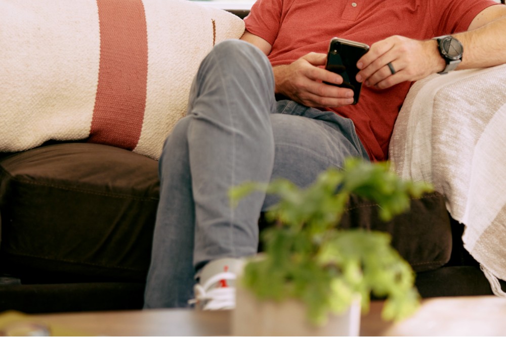 Man sitting on the couch and searching on his phone.
