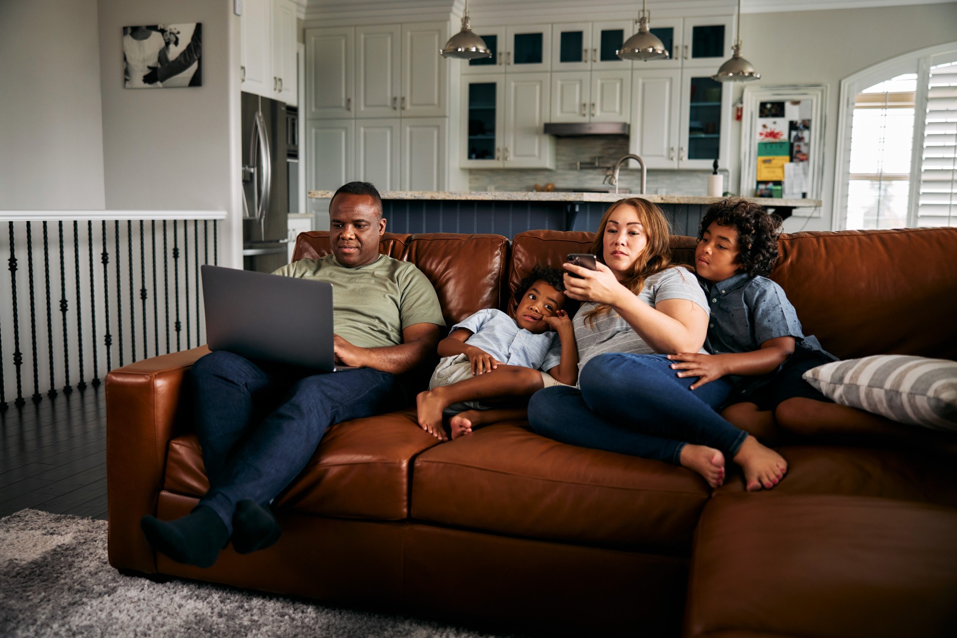 Family sitting on the couch and looking at their devices.