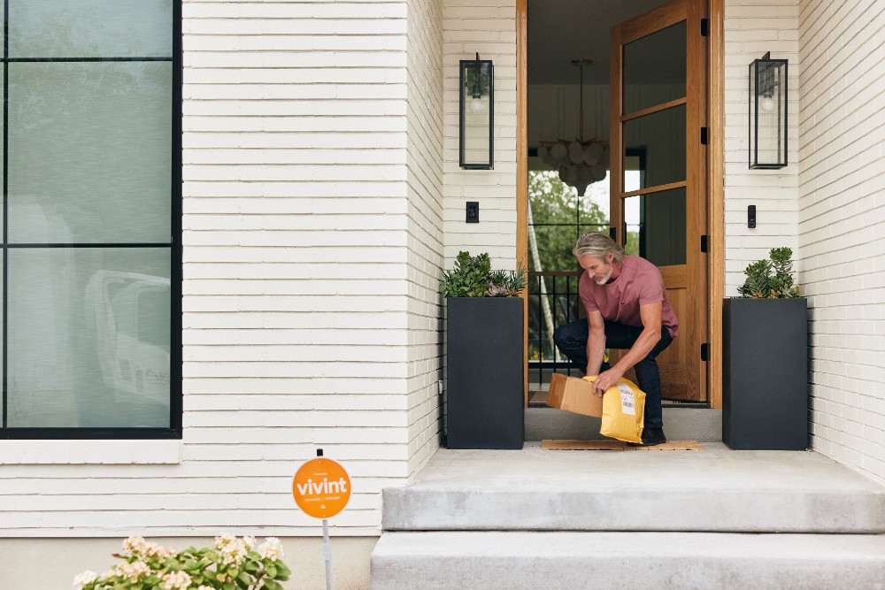 Homeowner grabbing packages from their front porch after their Doorbell Camera Pro notified them of the delivery.