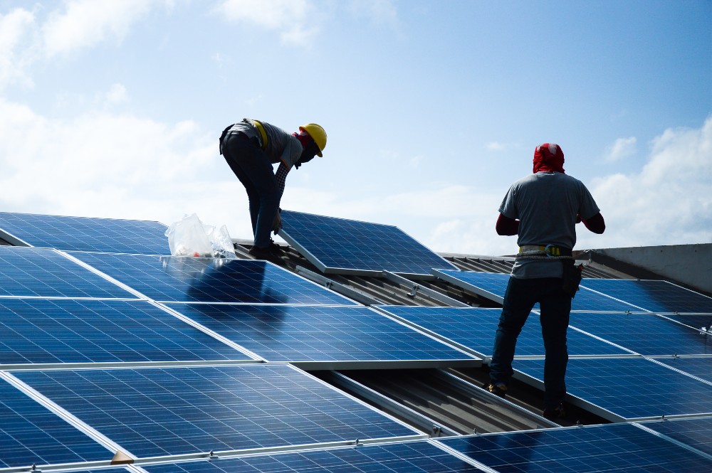 Two men installing solar panels on a home's roof.