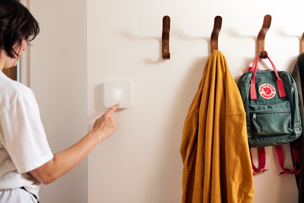 Woman adjusting the temperature on her smart thermostat.