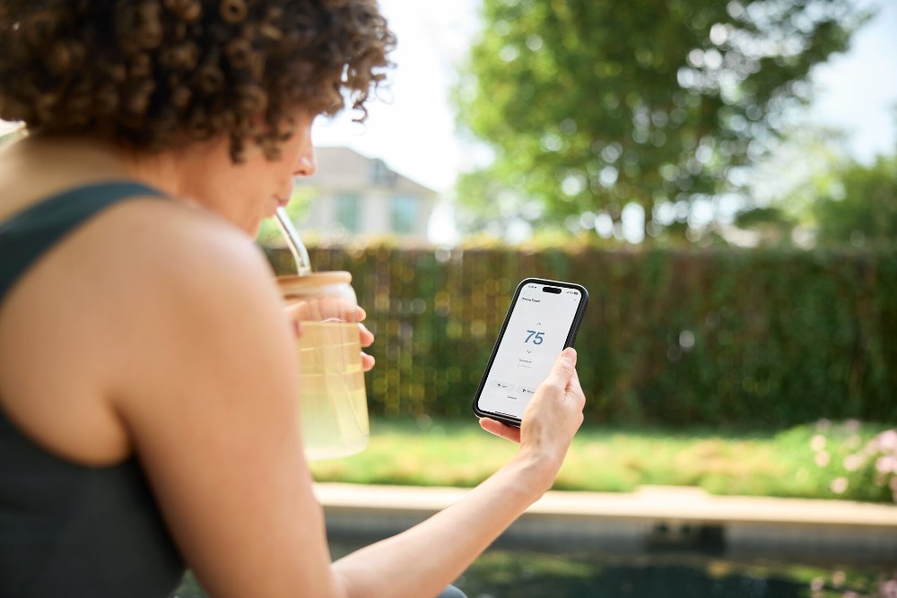 Woman checking on her thermostat in the Vivint app while on vacation.
