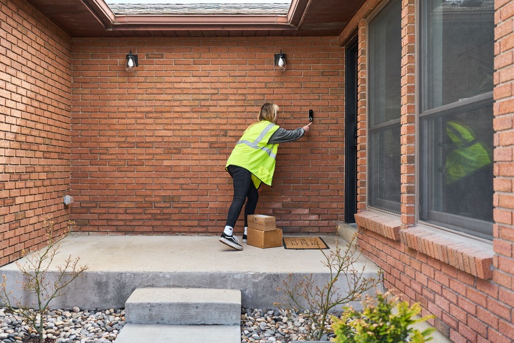 Delivery service person dropping off a package on a front porch.