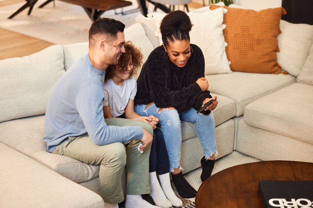 Parents watching a video on a cell phone with their child.