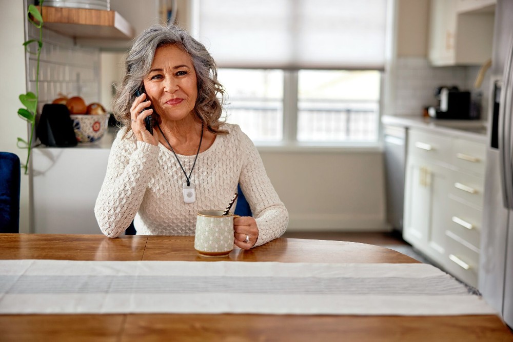 Woman who is wearing a Vivint senior alert pendant talking on the phone.