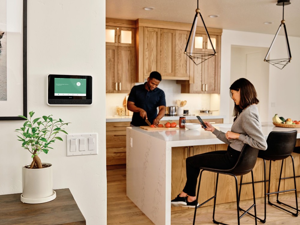 Couple cooking in their kitchen with a Vivint Smart Hub on the wall.