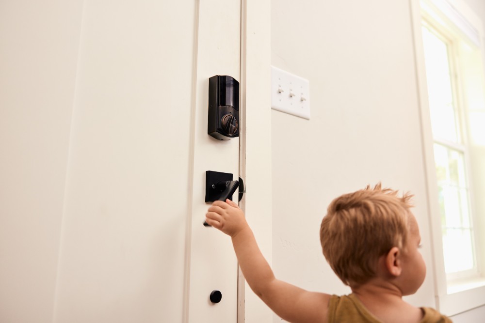 Toddler reaching for door handle on front door protected by a smart lock.