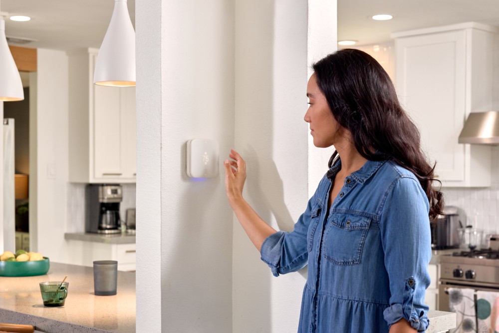 Woman adjusting her Vivint smart thermostat.