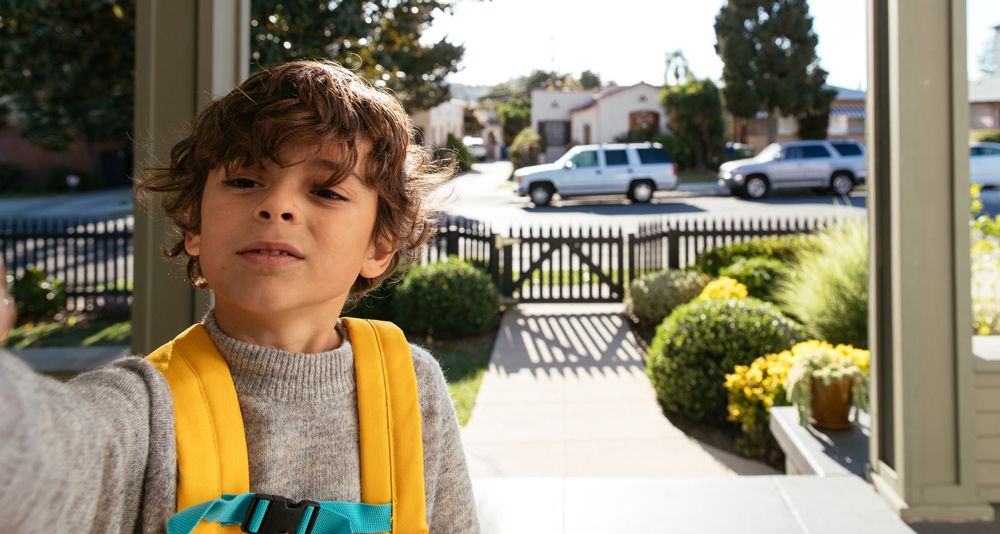 A boy types in a door code into a smart lock while the doorbell camera records him