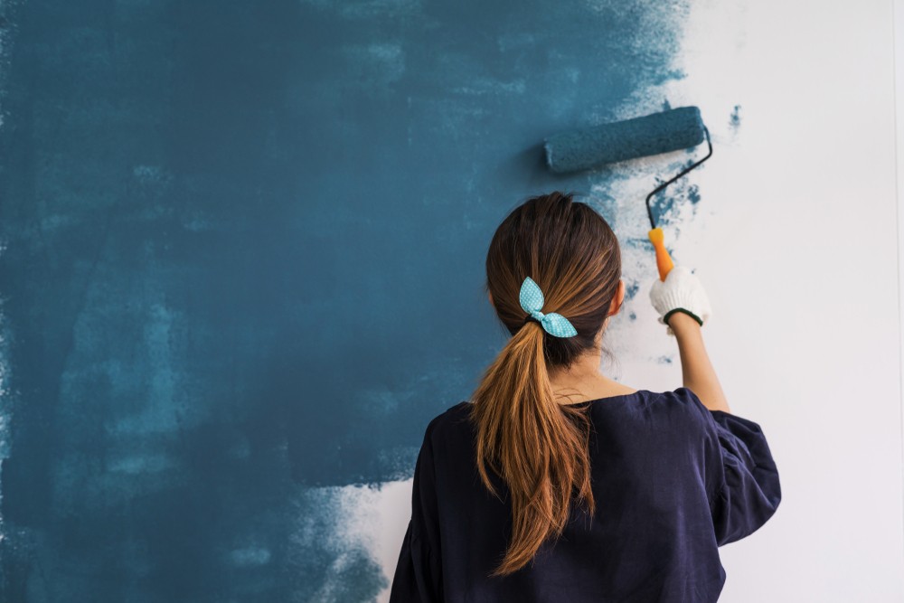 Woman painting a wall blue