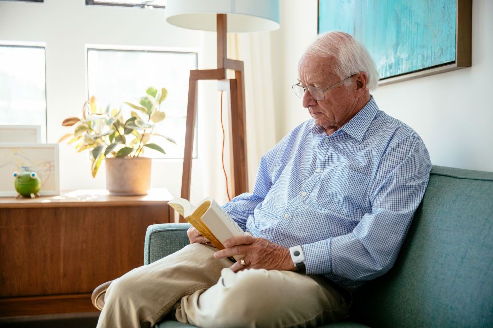 Elderly man with a Vivint panic pendant reading a book 