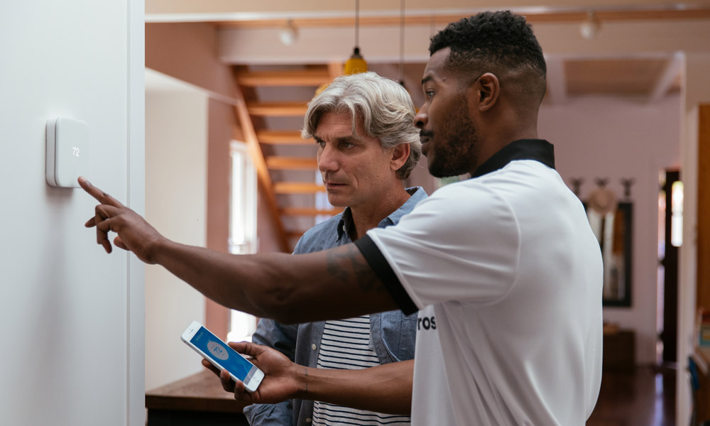Vivint professional showing a man how to use the Vivint Smart Thermostat
